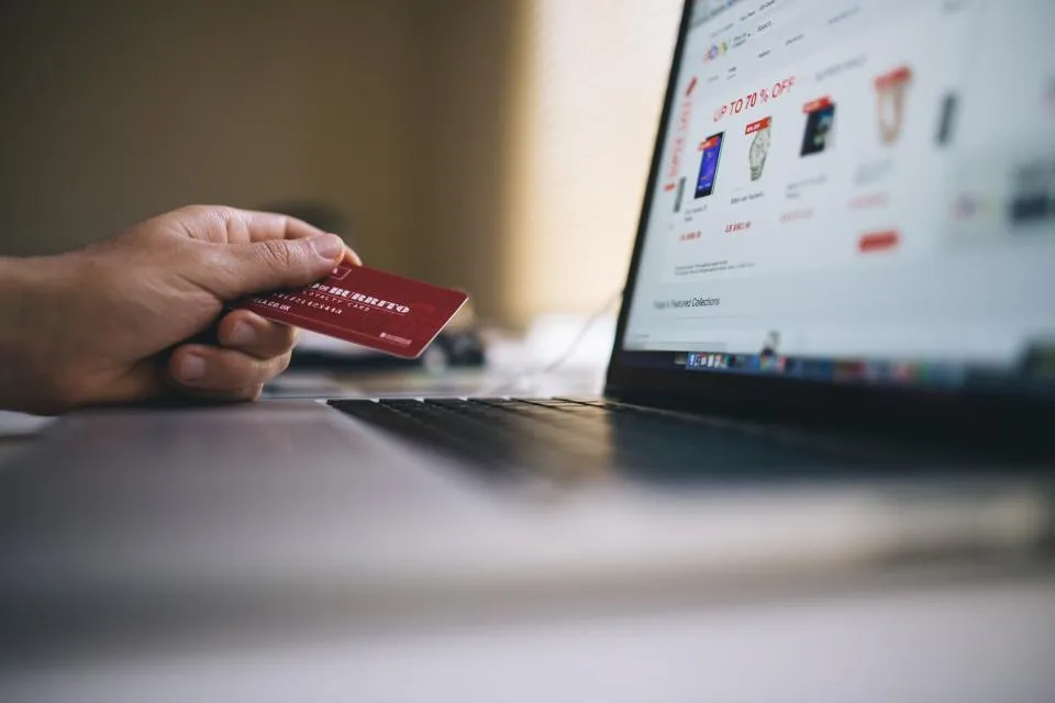 Shopper paying online with a card at a laptop