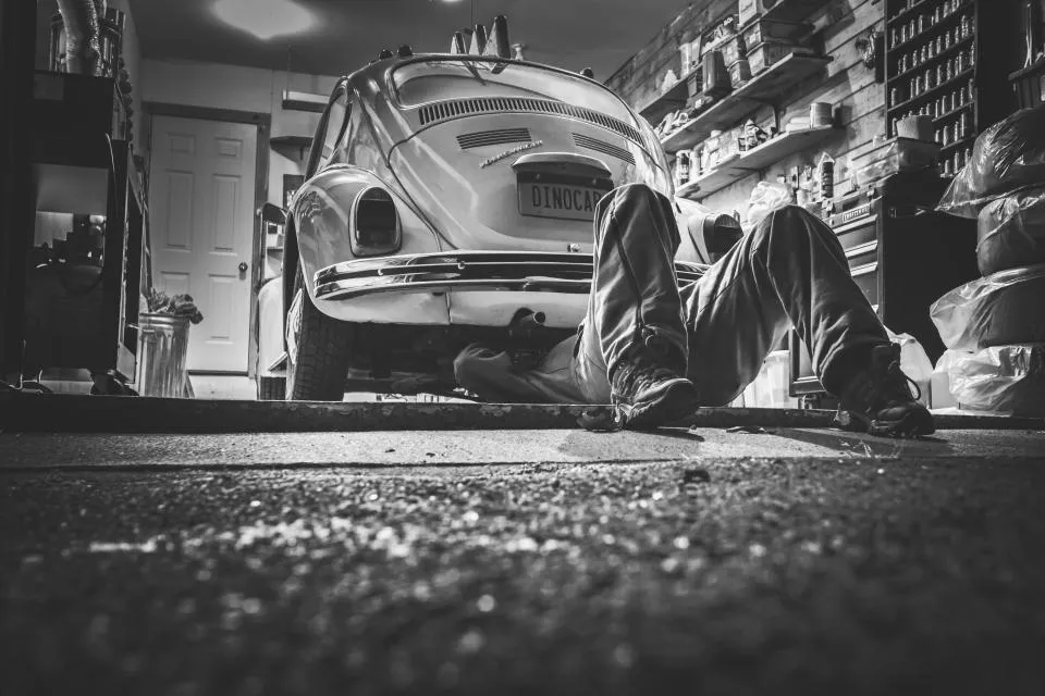 Technician working underneath a car in a workshop